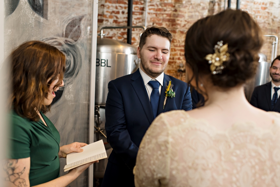 A groom holds his brides hands as he says I do.